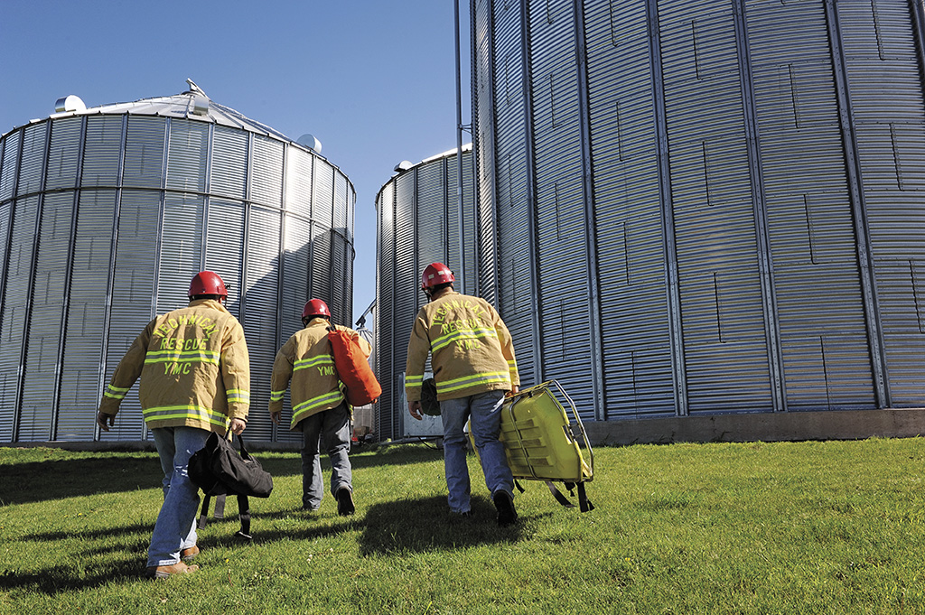 Three firefighters walking towards grain silos